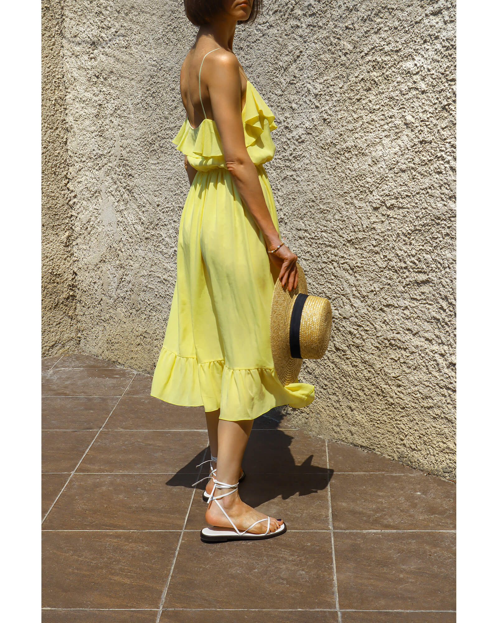 Back view of a lemon yellow ruffled midi dress with fine shoulder straps.