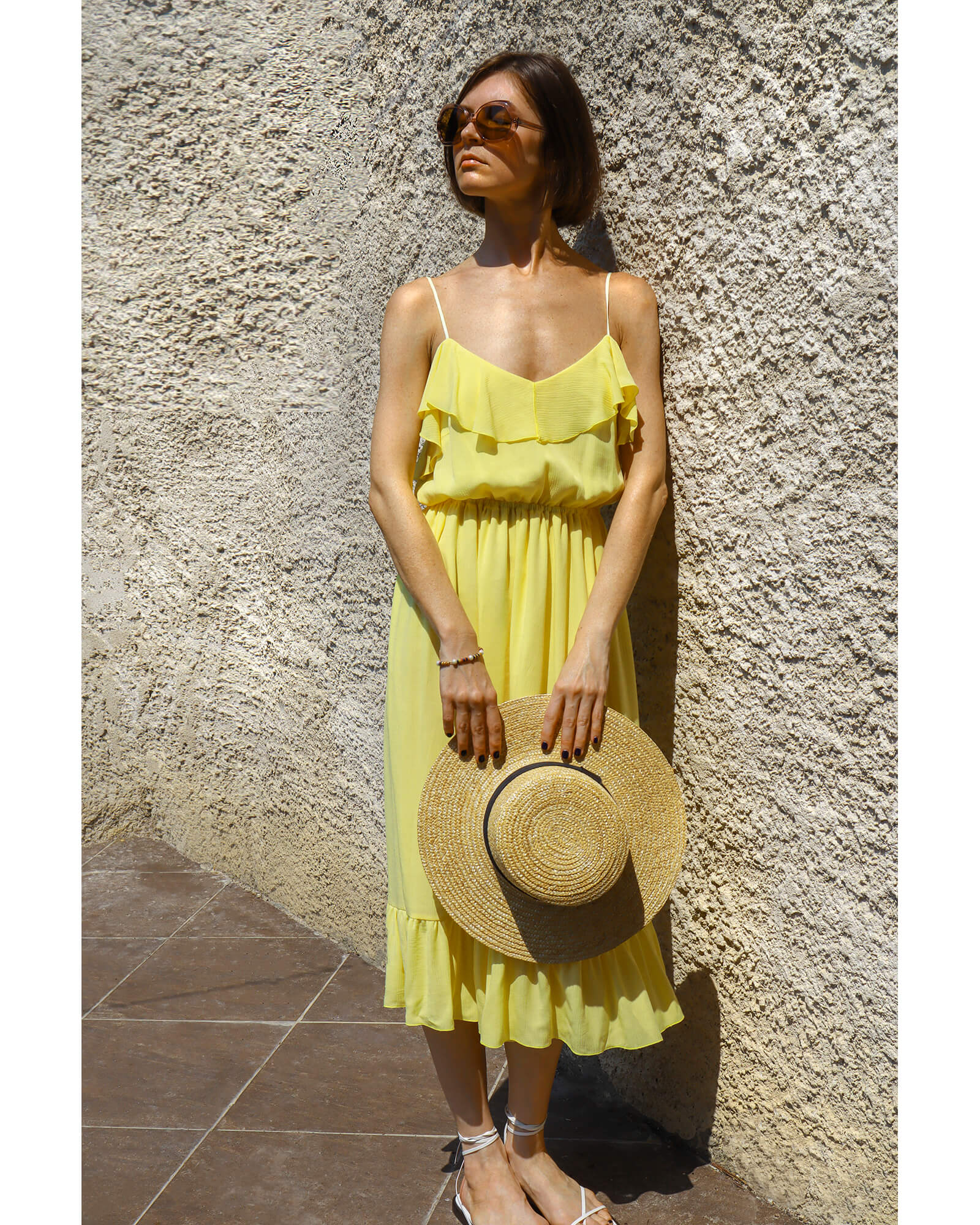 Model wearing a flowing yellow midi dress with ruffle details.