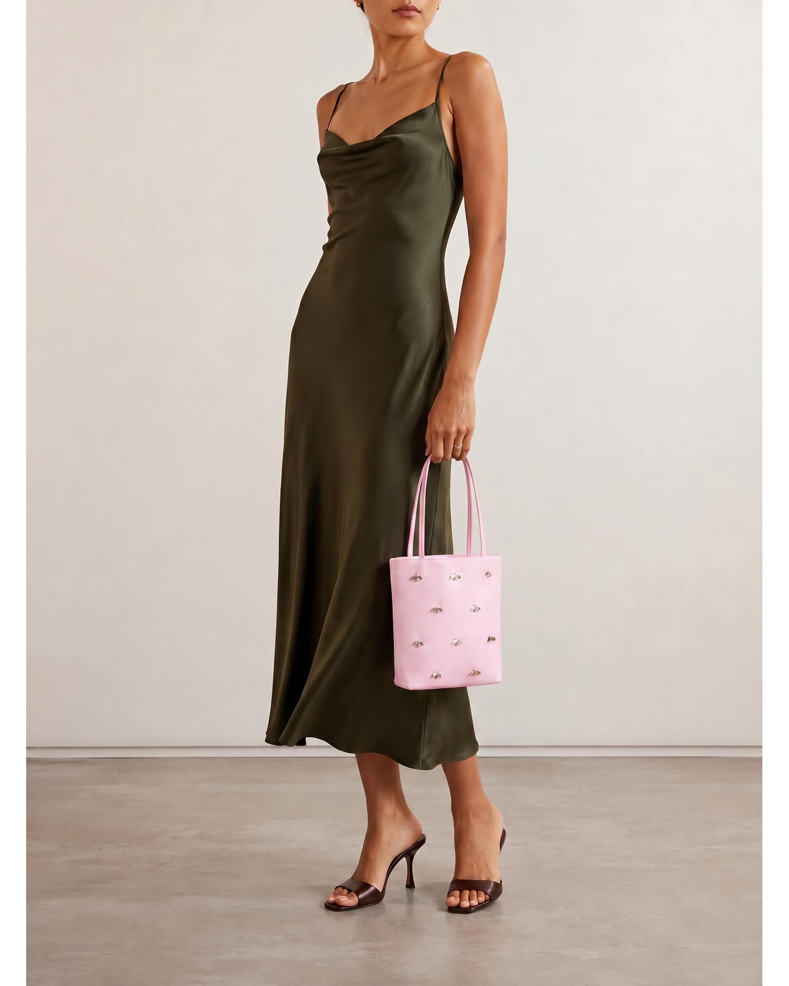 Model holding a pink embellished satin mini tote bag to showcase its scale and size.