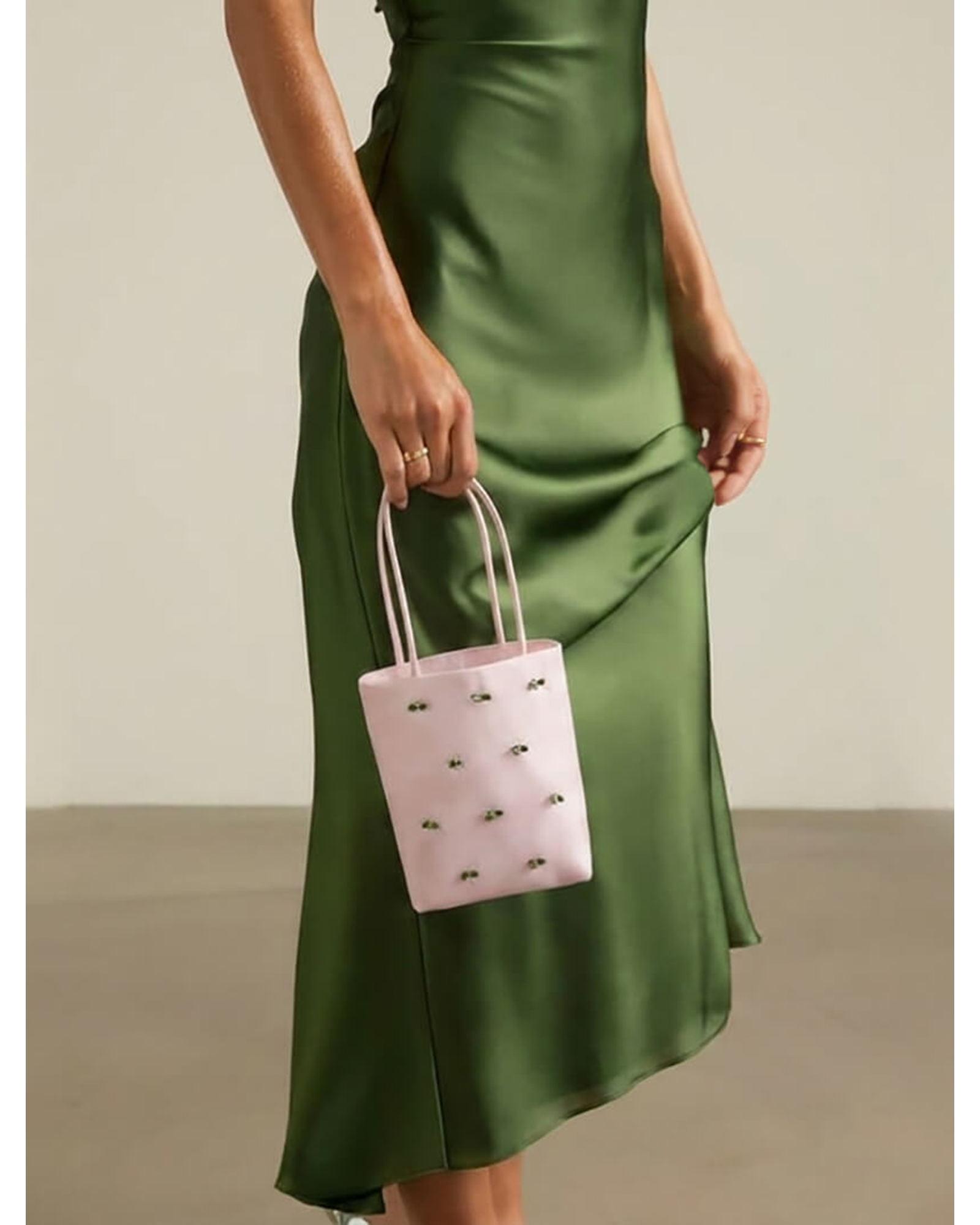 Model holding a pink embellished satin mini tote bag to showcase its scale and size.